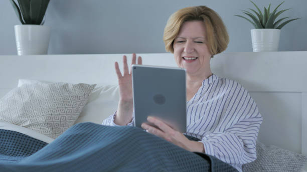 online video chat on tablet by tired old woman in bed - 16707 imagens e fotografias de stock