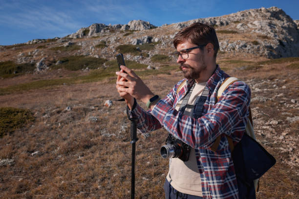 istock Young man taking photographs with digital camera in a mountains. 1338703640