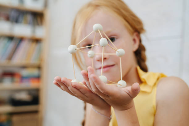 istock Pretty ginger girl presenting 3d shape she made from plasticine and toothpicks 1338704086