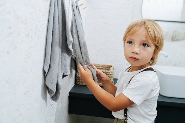 istock Cute little boy drying his hands in the bathroom. Side view. 1338704093