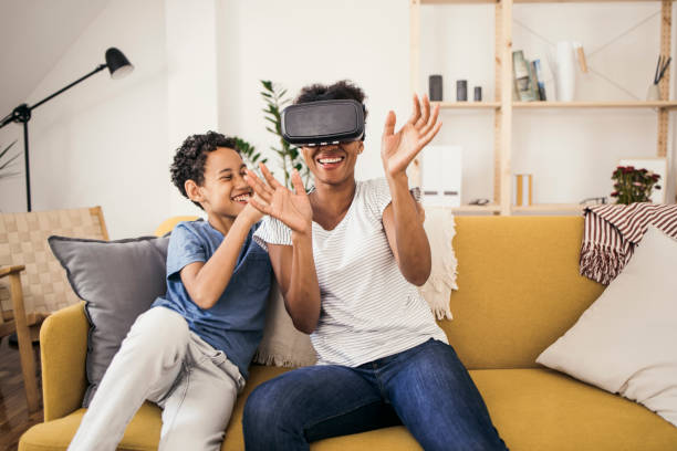 madre e figlio che usano un auricolare per la realtà virtuale e si divertono - video game family child playful foto e immagini stock