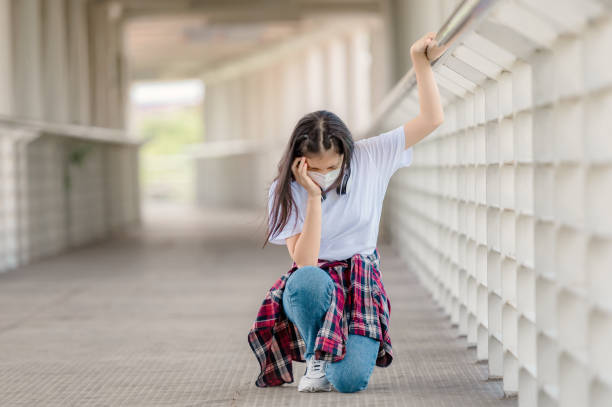 An Asian girl wearing a mask walks on an overpass with headaches, sudden fainting from debilitating conditions, and fever from coronavirus An Asian girl wearing a mask walks on an overpass with headaches, sudden fainting from debilitating conditions, and fever from coronavirus. Sudden Dizziness stock pictures, royalty-free photos & images