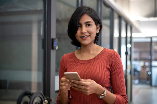 istock Smiling female business executive with smart phone in modern office 1338705723