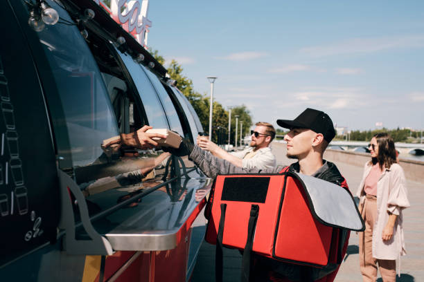 istock Young food delivery service staff putting packed orders into large bag 1338708353