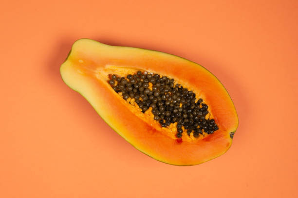 istock Papaya fruit on a orange background. Half papaya. 1338708635