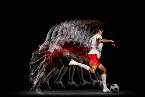 istock Stroboscope effect. Game. Young professional football player isolated on black background playing 1338709139