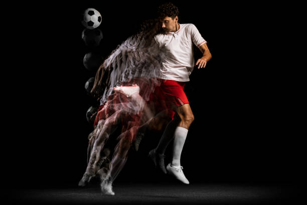 istock Young professional athlete playing football isolated on black background. Stroboscope effect 1338709158