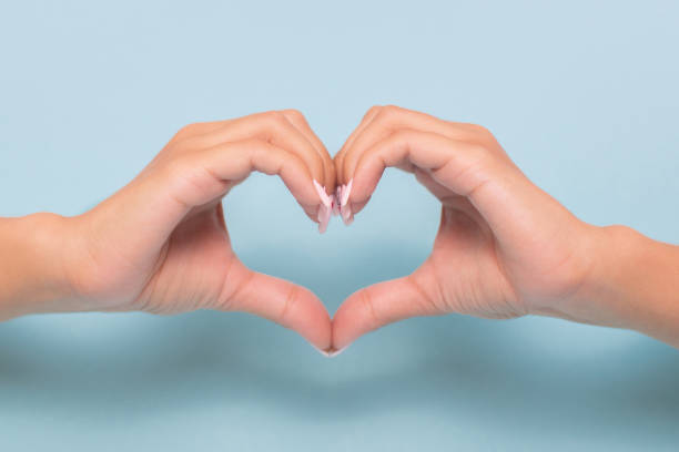 istock Beautiful female hands in heart shape on blue background 1338709411