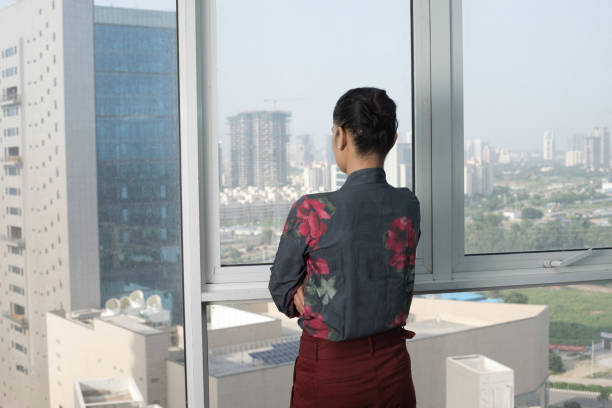 istock Woman looking out through window 1338710514