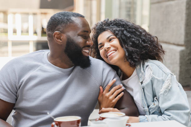 jovens cônjuges de casal afro-americano feliz conversando enquanto bebem café em encontro romântico no café. amor e relacionamento, confiança e conceito de vínculo - women heterosexual couple love men - fotografias e filmes do acervo