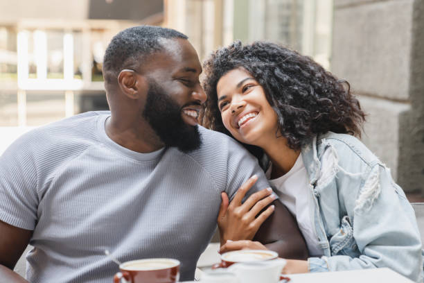 молодые счастливые афроамериканская пара супругов общаются вместе во время питья кофе на романтическом свидании в кафе. концепция любви и  - heterosexual пара стоковые фото и изображения