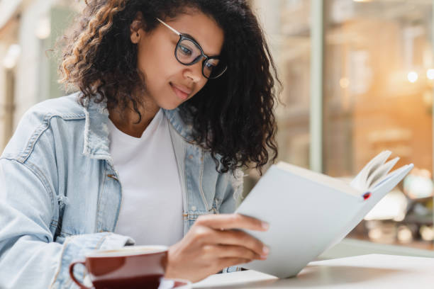 jovem estudante afro-americana freelancer mulher de negócios adolescente fazendo lição de casa, projeto, preparando-se para teste, exame on-line remotamente no café da cidade ao ar livre. - nerd student female exam - fotografias e filmes do acervo