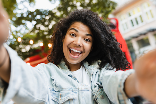 Joven afroamericana chica estudiante independiente tomando foto selfie en teléfono inteligente hablando en conversación de videollamada en el café del parque de la ciudad al aire libre photo