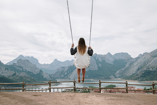 Rear view of a woman on a swing in a beautiful mountain landscape