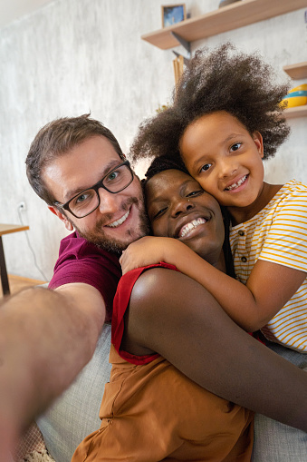 Young interracial family with child taking selfie at home