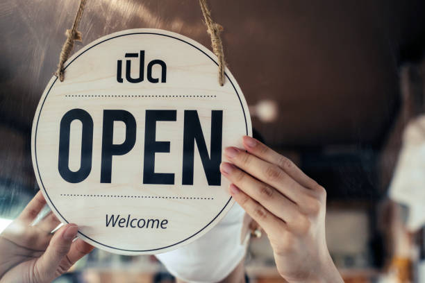 istock asain staff woman wearing protection face mask turning open sign board with thai language on glass door in cafe coffee shop, hotel service, cafe restaurant, retail store, small business owner concept 1338717841