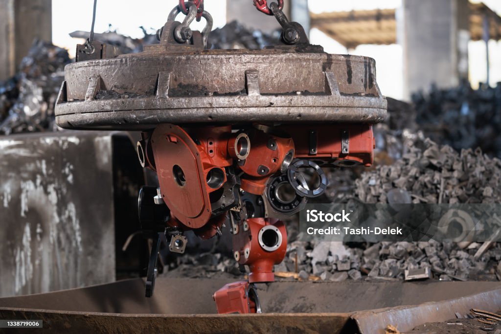 Transporting Scrap Steel By Crane, Recycling Of Material Transporting scrap steel by crane. Magnetic device attracts iron. Recycling of material. Production factory, metal industry and engineering concept. Recycling Stock Photo