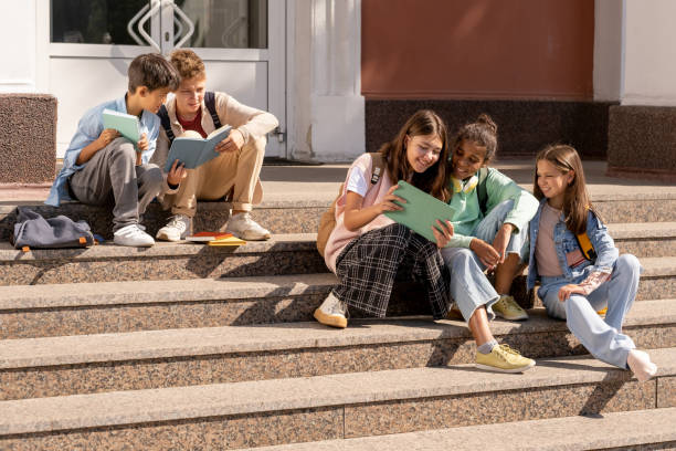istock Group of adolescent schoolkids using tablets while sitting on staircase 1338720235
