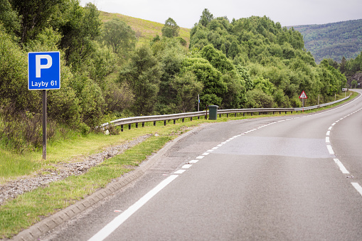 A sign in front of an empty layby on a winding section of the A9 in Scotland.