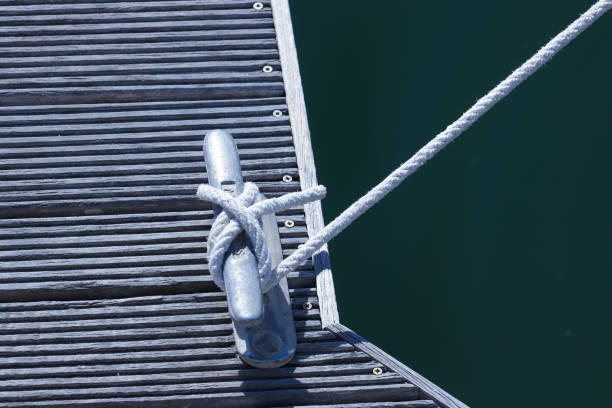 cuerda de barco atada a un taco de metal en el muelle de tablones de madera. - moored nautical equipment circle rope fotografías e imágenes de stock