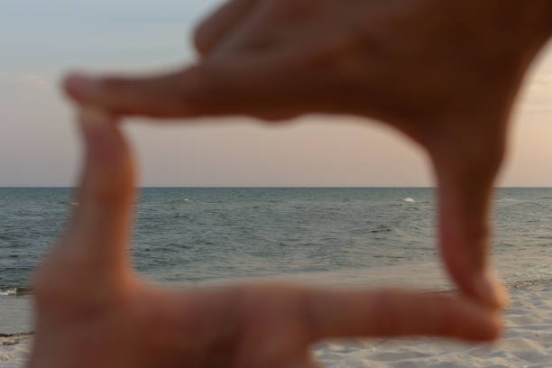 unfocused human hands making frame against sea. future planning hands gesture with seacoast, focus on background. composition fingers frame. summer inspiration. idea and imagination gesture. - imagination creativity finger frame frame imagens e fotografias de stock