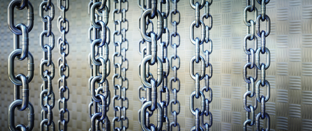 A screen of shiny chains hanging vertically on a defocused metal grate background. Wide horizontal composition.