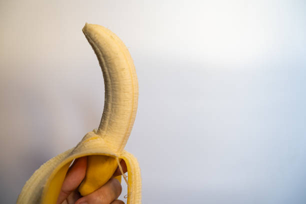 istock One ripe banana, peeled, held in hand 1338729541
