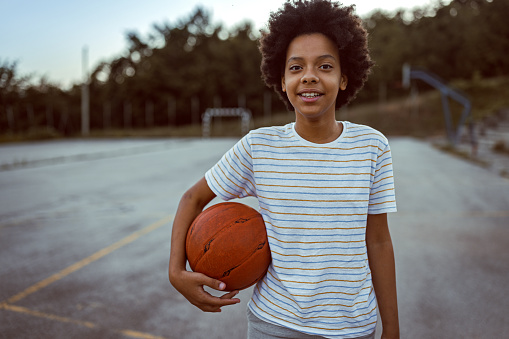 Photo of girl with basketball ball on sport court.