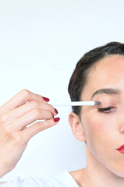 istock Young brunette woman applying eye make-up, white background with copy space 1338730927