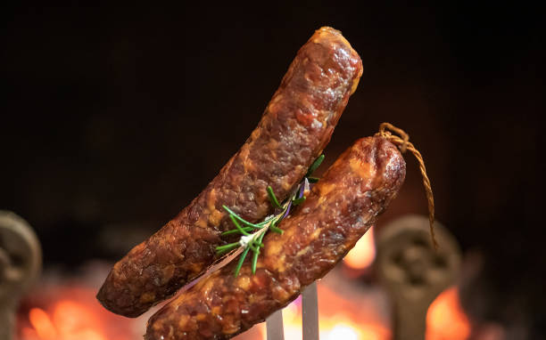 istock Sausages on a large fork baking on the fireplace heat at home 1338733336