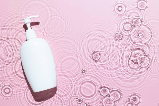istock Pink water texture surface with white bottle on podium, ripples and transparent at sunlight. Backdrop for cosmetic or spa concept background. Copy space 1338735000