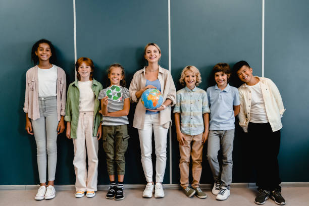 scolari compagni di classe bambini alunni studenti in piedi con l'insegnante che tiene il globo e il segno di riciclaggio alla classe di lezione della scuola di geografia. eco-attivisti. protezione dell'ambiente. - learning child education globe foto e immagini stock