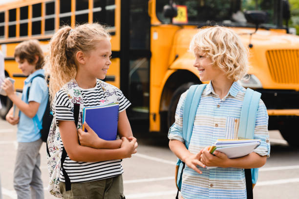 istock Two small kids classmates pupils schoolchildren talking communicating discussing learning classes lessons homework after summer holidays at the school yard next to the school bus 1338736130