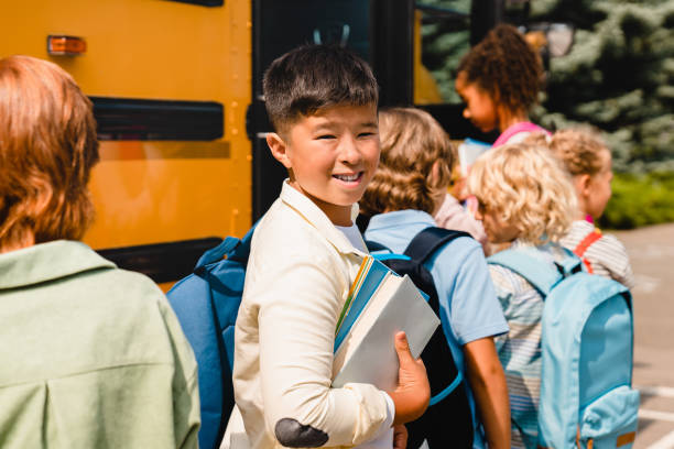 중국계 한인여학생학생이 신입생 학기 학습을 준비하는 기숙학교 버스를 기다리는 급우들과 줄을 서 있다. - back to school child first day of school school bus 뉴스 사진 이미지