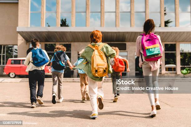 Little Kids Schoolchildren Pupils Students Running Hurrying To The School Building For Classes Lessons From To The School Bus Welcome Back To School The New Academic Semester Year Start Stock Photo - Download Image Now