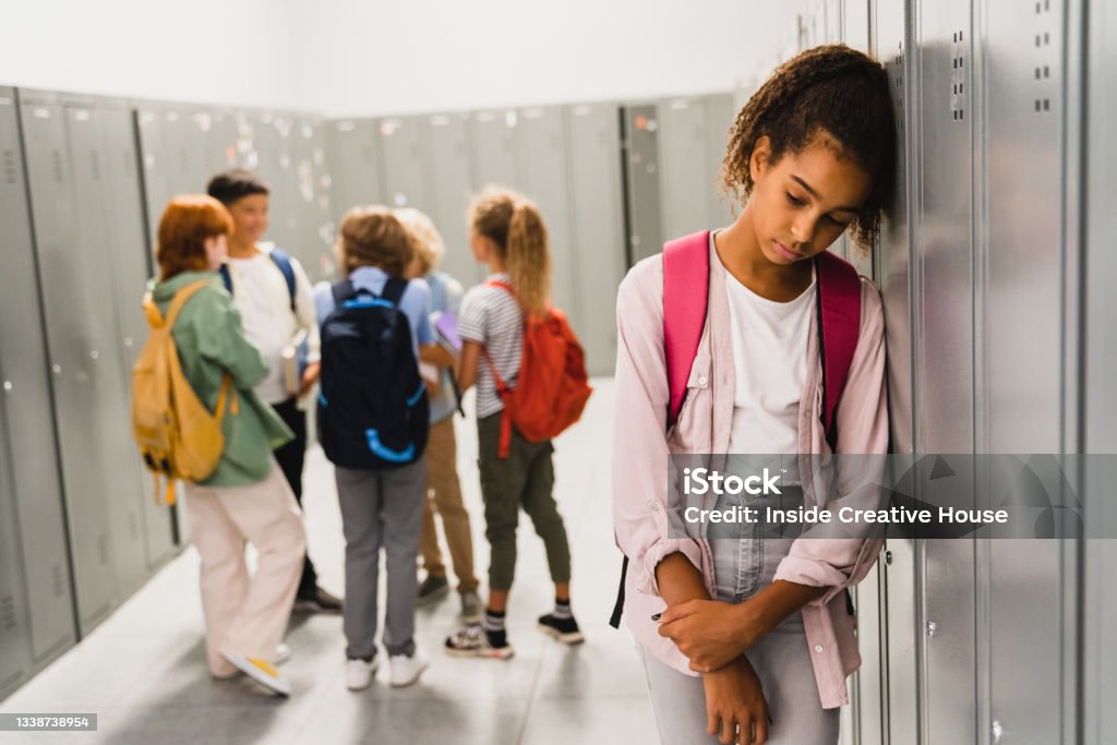 Lonely sad african-american schoolgirl crying while all her classmates ignoring her. Social exclusion problem. Bullying at school concept. Racism problem Racism Stock Photo