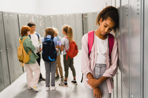 lonely sad african-american schoolgirl crying while all her classmates ignoring her. social exclusion problem. bullying at school concept. racism problem - 獨處 個照片及圖片檔