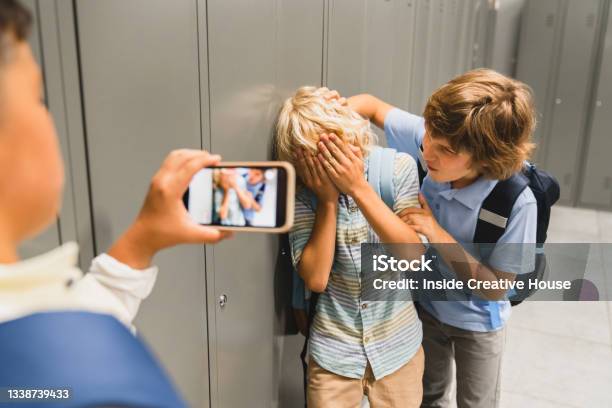 Schoolchildren Cruel Boys Filming On The Phone Torturing Bullying Their Classmate In School Hall Puberty Difficult Age Stock Photo - Download Image Now