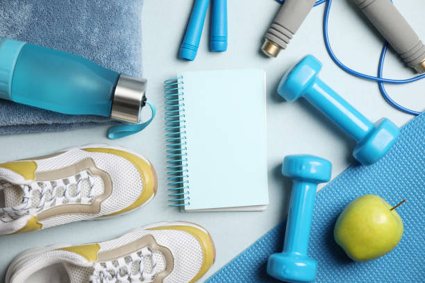 istock Flat lay composition with fitness equipment and notebook on light blue background, space for text 1338740396