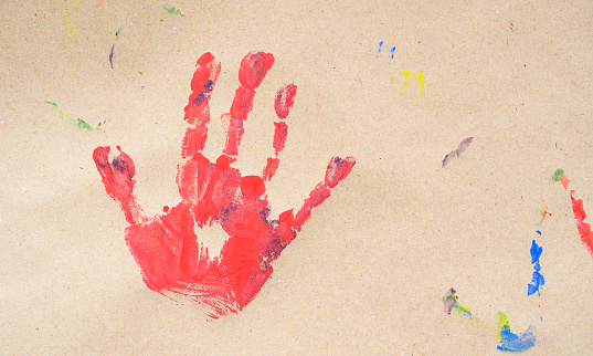 imprint red color child hand isolated on brown paper. Close up. copy space. Creative, funny, artistic and happy