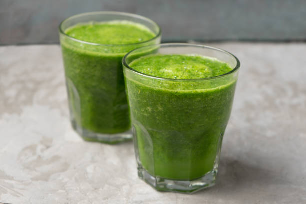 istock Green juice in glass on grey background 1338744324