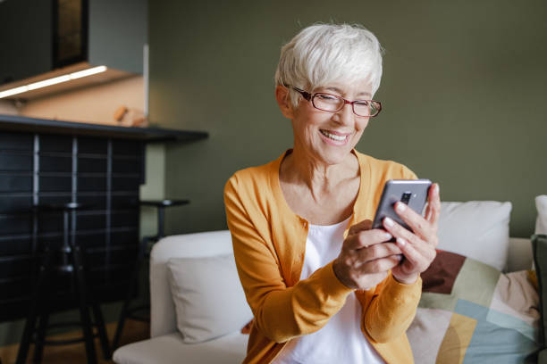 istock Senior woman uses a mobile phone at home 1338747421