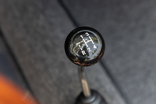 Vintage knob of classic sports car shows the 4 gears and reverse of a manual transmission stick shift automobile.