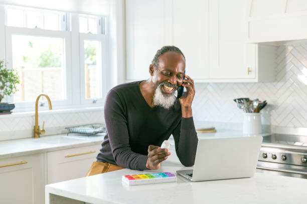 uomo di colore anziano che parla al telefono con il suo medico di farmaci da prescrizione - healthcare and medicine home interior medicine geriatrics foto e immagini stock