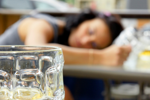 Alcohol abuse: drunk young woman or student lying down on a table with beer bock still in hand, focus on glass up front. More real people at: http://tonytremblay.com/sylvie/people.jpg