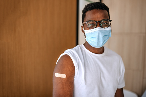 Man wearing protective face mask with a Adhesive Bandage on his hand after receiving the covid-19 vaccine