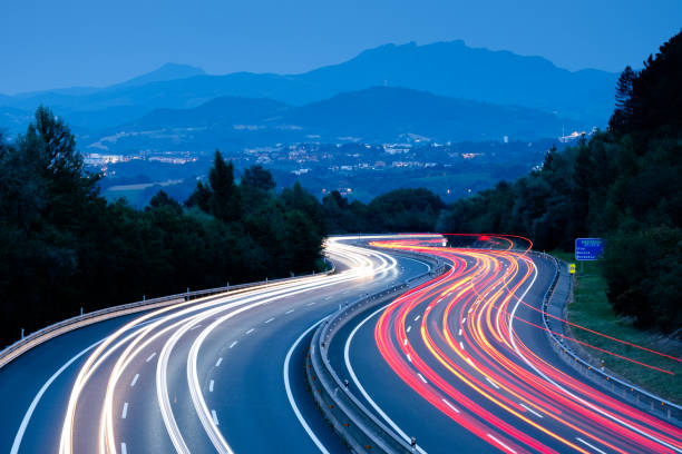 luces de coche al atardecer conduciendo a gran velocidad por la autopista, san sebastián, euskadi - vias publicas fotografías e imágenes de stock