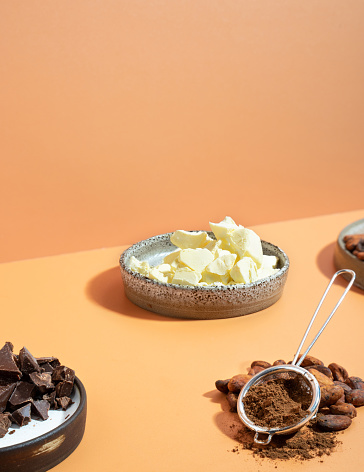 Creative isometric diagonal projection composition with healthy ingredient organic cocoa products: beans, powder,butter on a ivory background.Concept wellness, healthcare, energy superfood,brain food