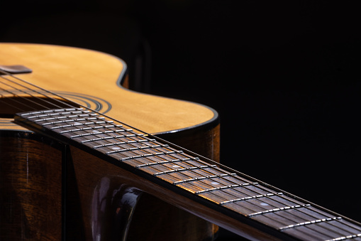 Acoustic guitar with a beautiful wood on a black background.
