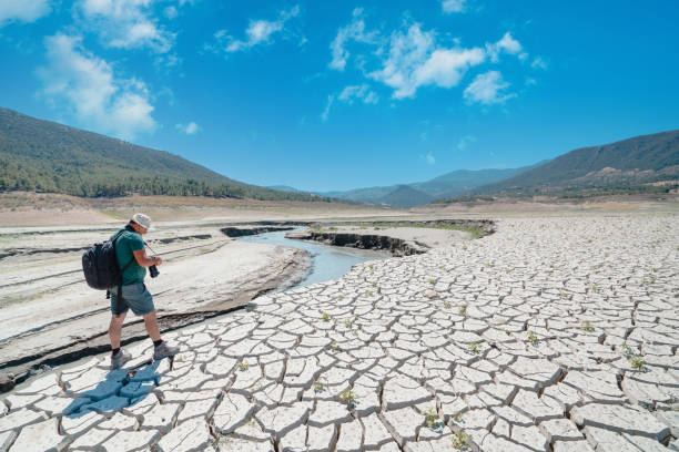 istock Photographer is taking photos on dried cracked drought lakebed surface 1338755780
